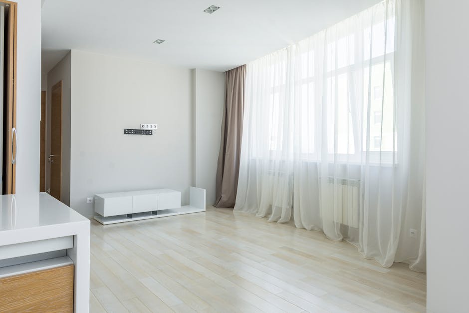 Bright modern minimalist apartment interior with large windows and sheer curtains.