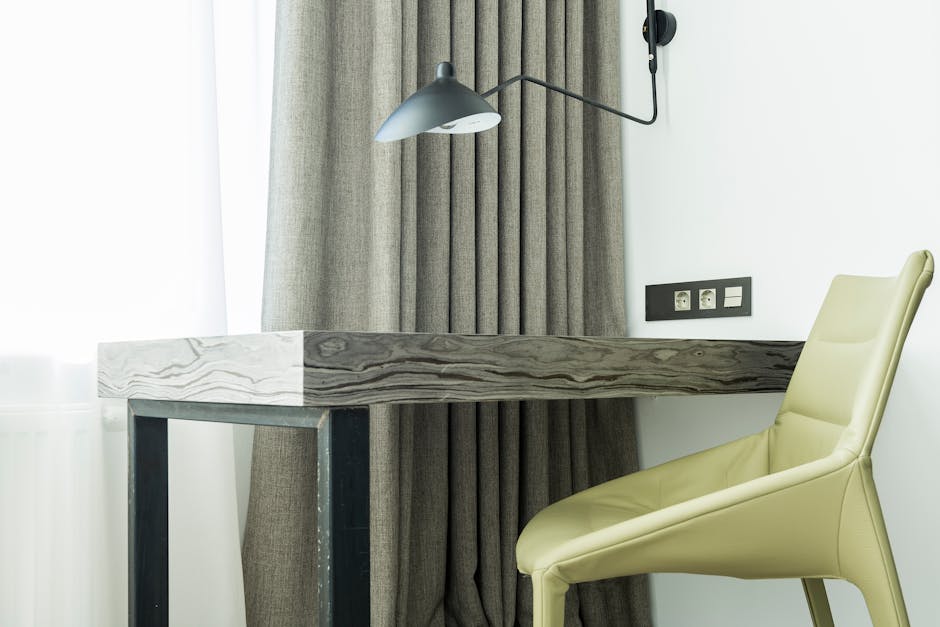 Stylish room with soft leather chair near wooden table and window behind curtain